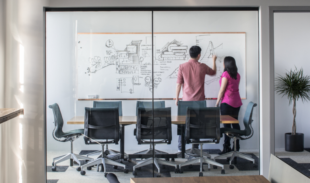 Two People Whiteboarding In A Confrence Room